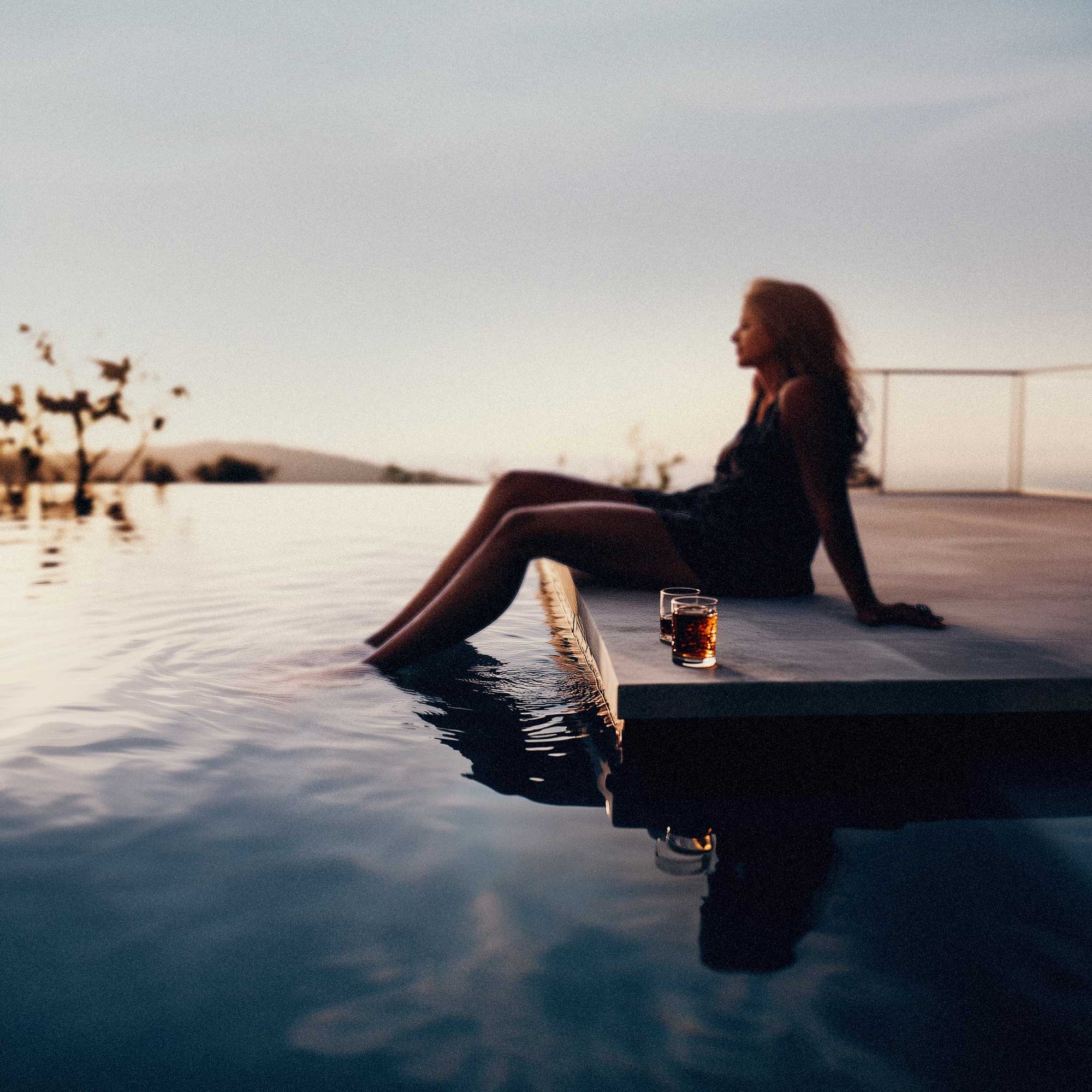 Driftology woman drinking sleep-friendly nightcap by the pool